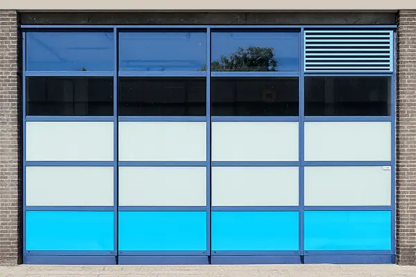 Industrial sectional overhead door featuring customized blue and white panels with ventilation.