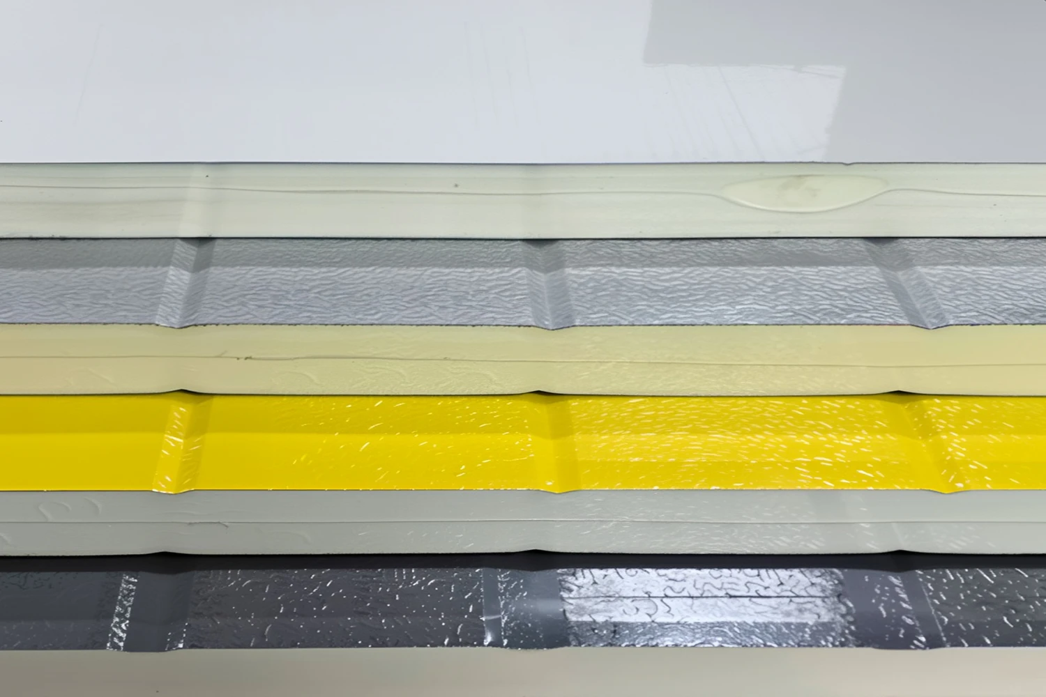 Cross-section of four different colored heavy-duty steel back garage door panels, highlighting the high-density PU foam core that maximizes thermal efficiency and ROI.