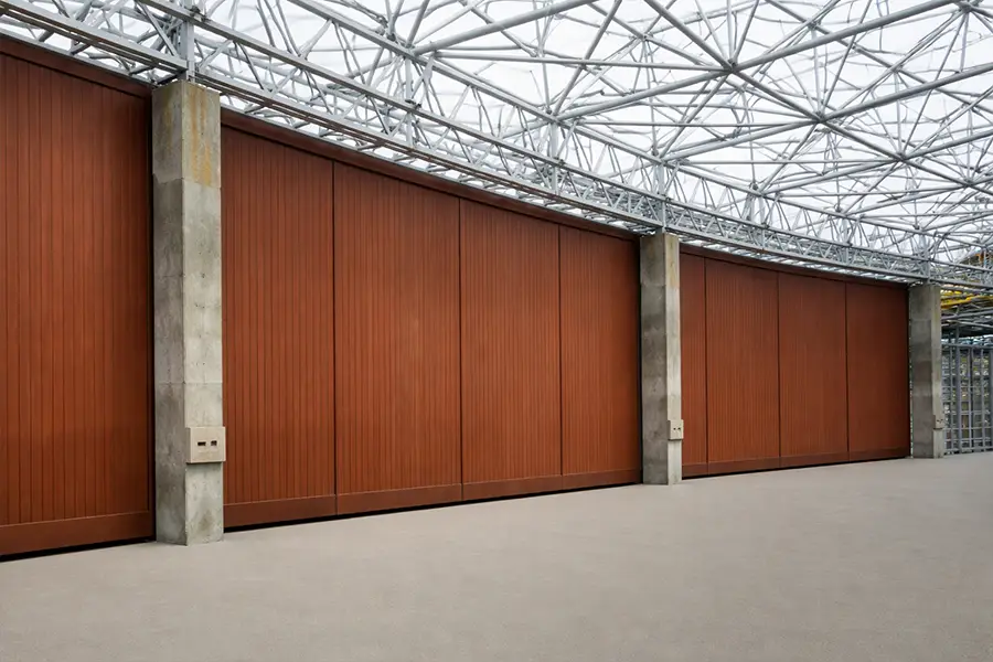Custom brown finish steel hangar doors designed for high-end aviation facilities with heavy-duty truss structures.