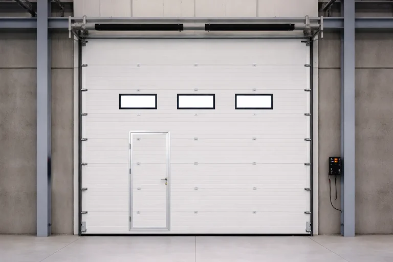 Interior view of an energy-efficient industrial sectional door featuring a built-in wicket door and vision panels for optimized facility access.