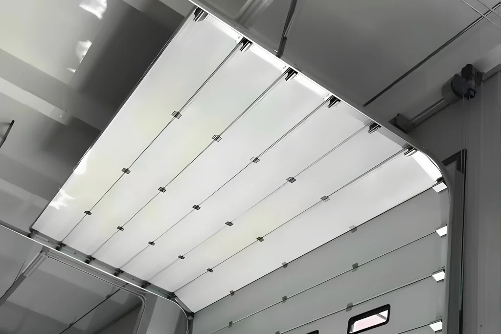 Interior view of a white sectional door operating on heavy-duty commercial garage door tracks, featuring galvanized hardware and an industrial window kit supplied by ABX.