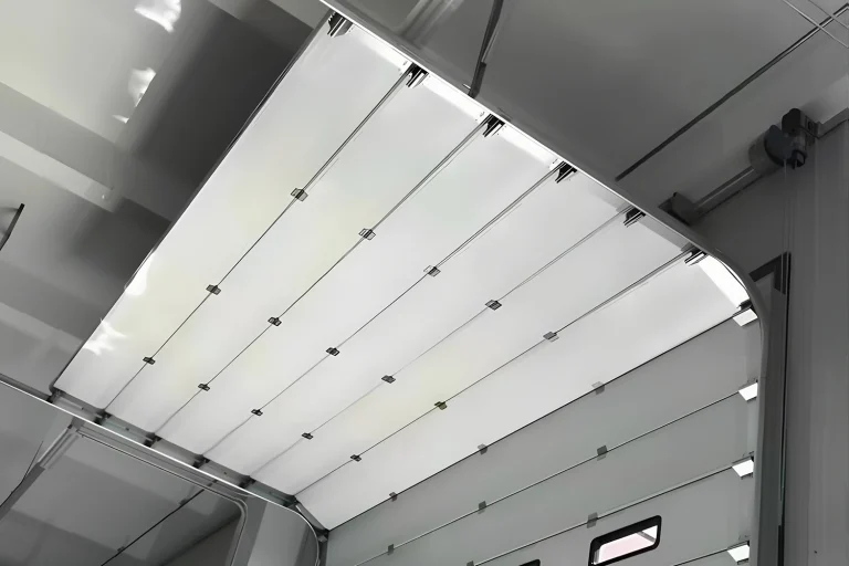 Interior view of a white sectional door operating on heavy-duty commercial garage door tracks, featuring galvanized hardware and an industrial window kit supplied by ABX.