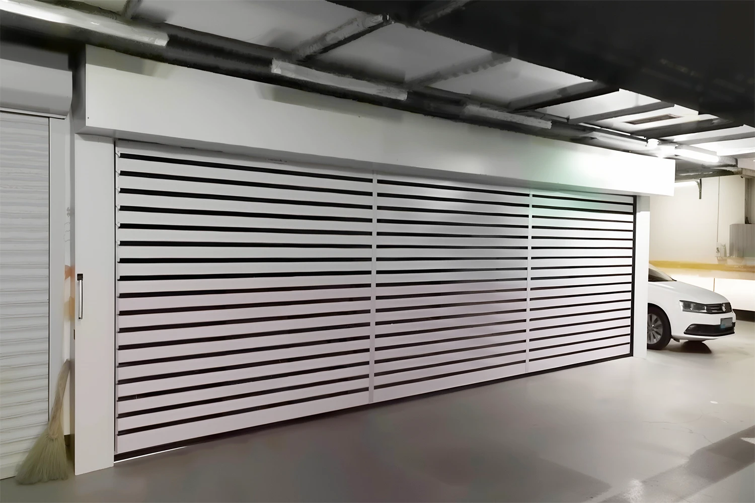 A wide, heavy-duty commercial roll-up garage door installed in an indoor parking facility, manufactured by ABX for secure and high-speed access control.