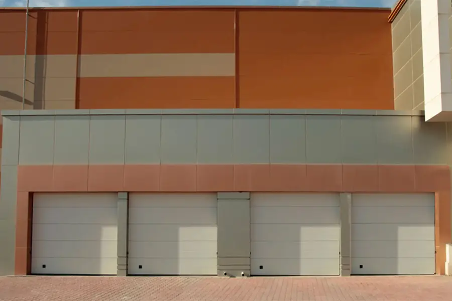 Multiple white sectional commercial garage doors installed at a large industrial warehouse facility.