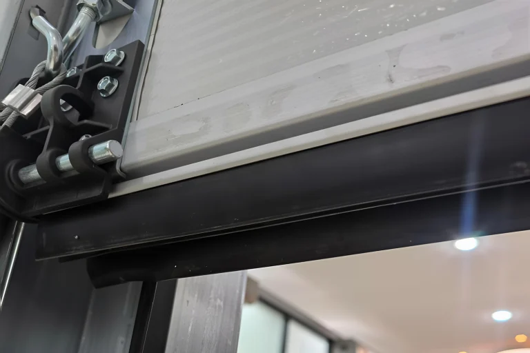 Technical illustration from a wholesale manufacturer guide showing a cross-section of a high R-value insulated commercial overhead door with a heavy-duty floor seal, optimized for cold storage facility efficiency.